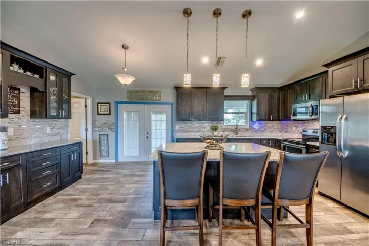 Kitchen featuring vaulted ceiling, stainless steel appliances, hanging light fixtures, tasteful backsplash, and dark brown cabinets