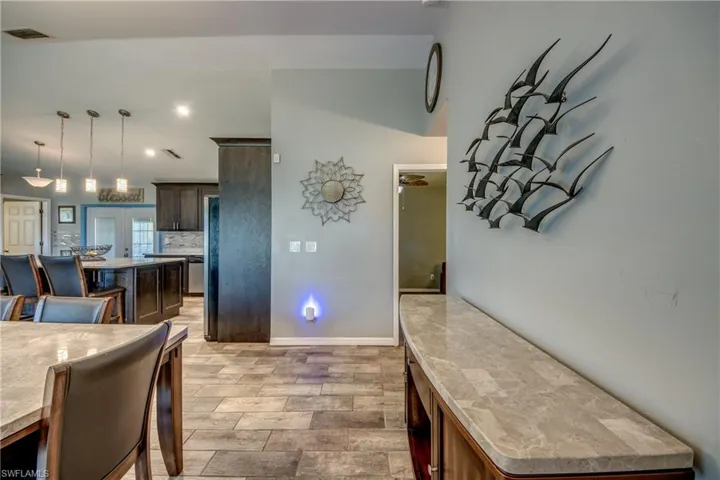 Kitchen with dark brown cabinets, french doors, pendant lighting, backsplash, and a center island