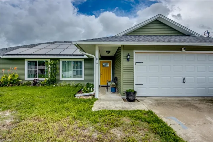 Single story home with a front yard, a garage, and solar panels