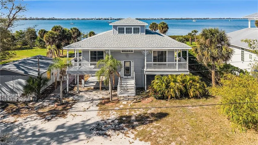 View of front of house featuring a water view, roof with shingles, and a balcony