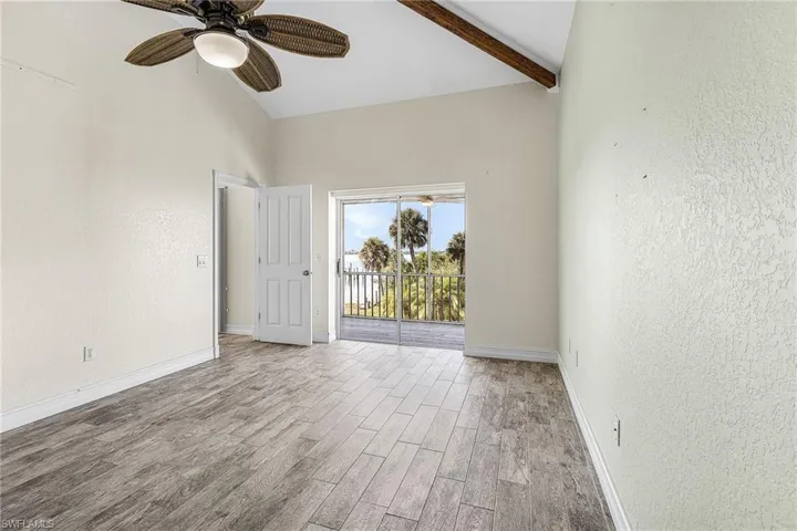 Empty room with wood tiled floors, ceiling fan, lofted ceiling, and a textured wall