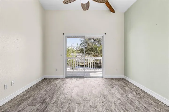 Empty room featuring wood finished floors, a ceiling fan, and lofted ceiling