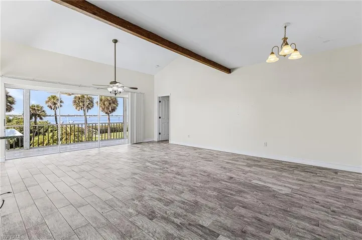 Unfurnished living room featuring wood tiled floors, hanging lights, vaulted ceiling, and a ceiling fan