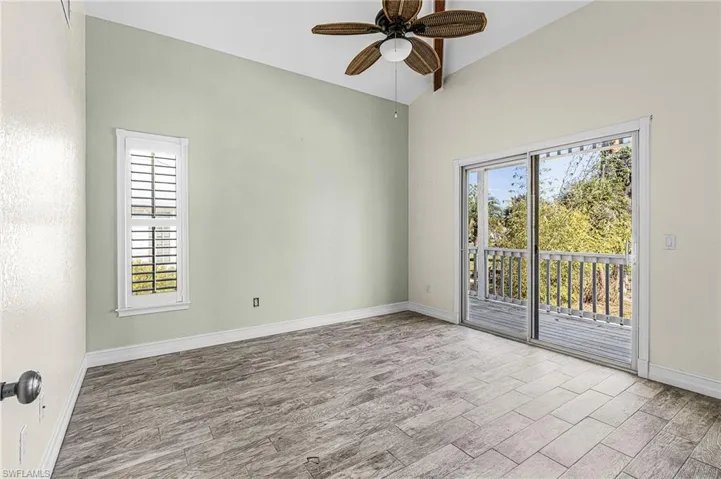 Empty room with wood tiled floors, a ceiling fan, and vaulted ceiling