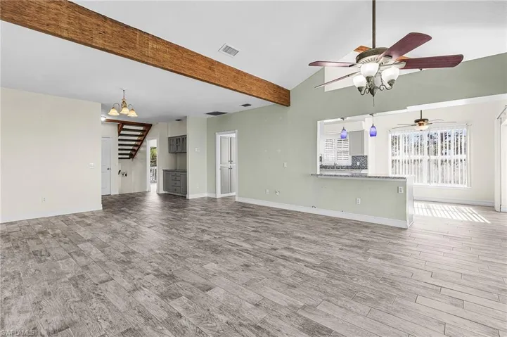 Unfurnished living room with suspended lighting, light wood-style floors, a ceiling fan, and vaulted ceiling