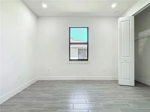 Unfurnished bedroom with wood finish floors, recessed lighting, a closet, and baseboards