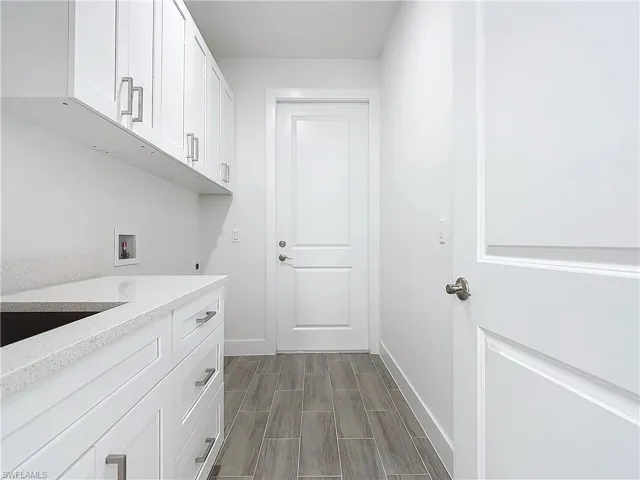Clothes washing area featuring cabinet space, baseboards, wood tiled floor, hookup for an electric dryer, and washer hookup