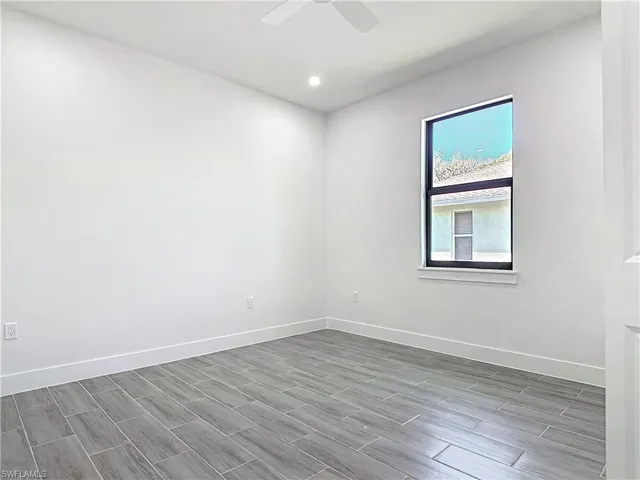 Empty room with baseboards, a ceiling fan, and wood finish floors