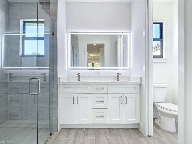 Bathroom with a stall shower, a sink, and a wealth of natural light