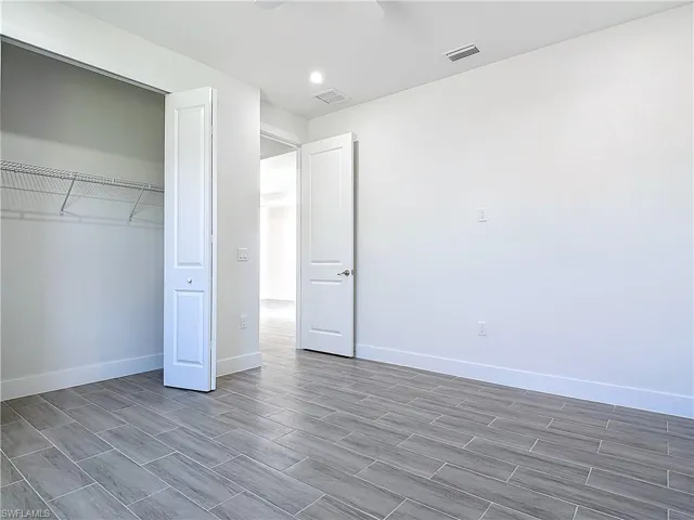 Unfurnished bedroom featuring baseboards, visible vents, a closet, and wood finished floors