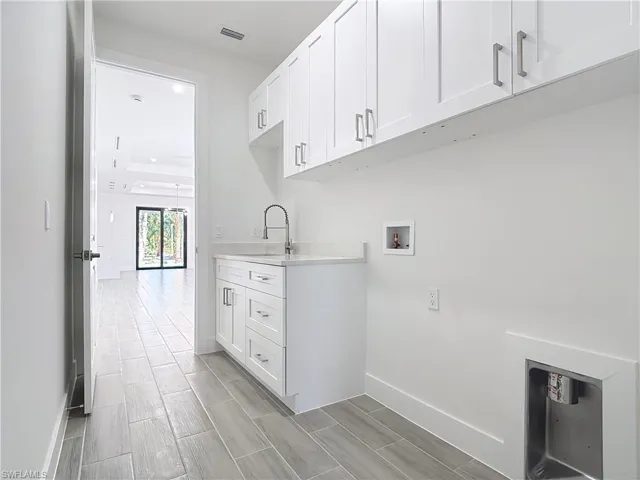 Laundry room with cabinet space, baseboards, visible vents, hookup for a washing machine, and a sink