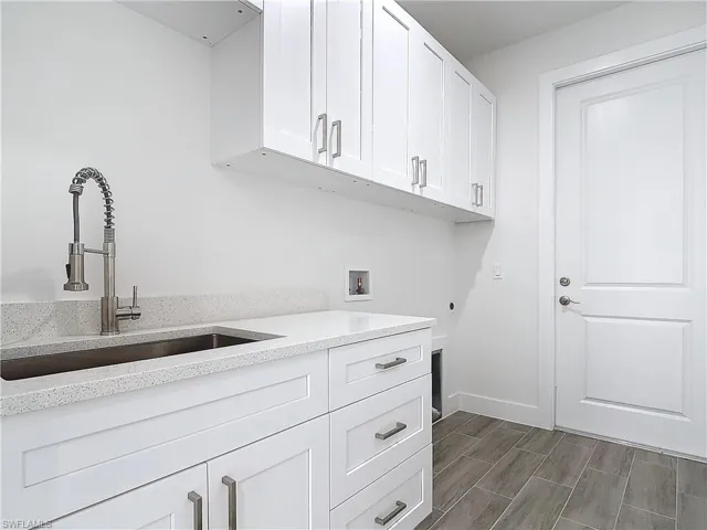 Laundry area featuring cabinet space, a sink, wood tiled floor, washer hookup, and electric dryer hookup