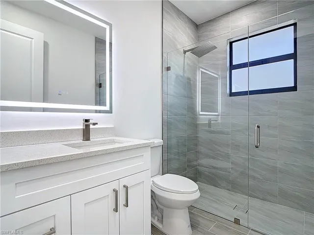 Full bath featuring toilet, a shower stall, and vanity