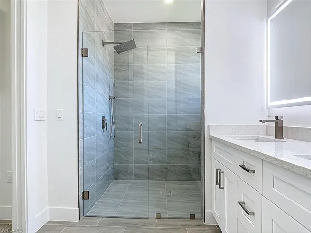 Full bath with a shower stall, baseboards, and vanity