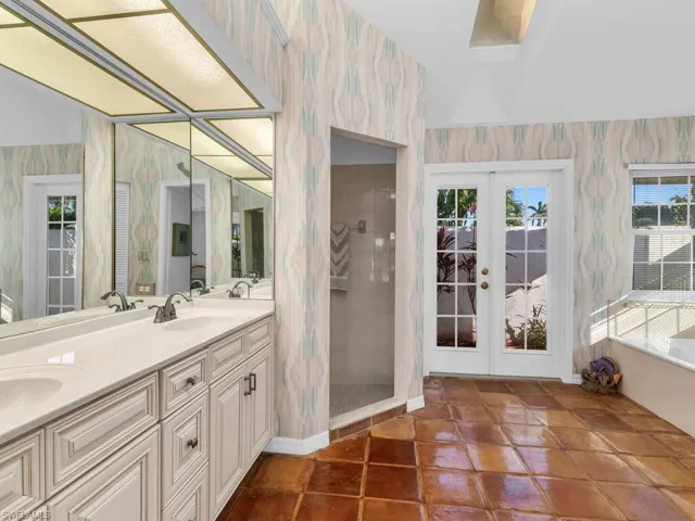 Bathroom with vanity, tile patterned flooring, french doors, and tiled shower