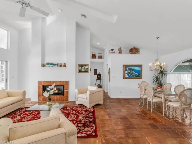 Living room featuring ceiling fan with notable chandelier, high vaulted ceiling, and a tile fireplace