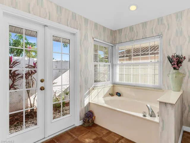 Bathroom with tile patterned flooring, french doors, and a bathing tub
