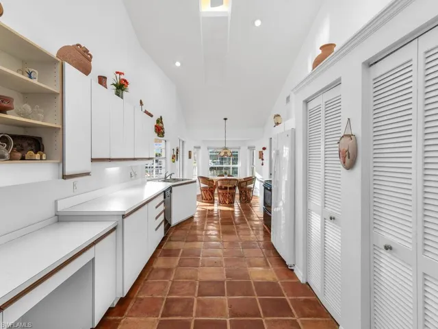 Kitchen with lofted ceiling, white cabinetry, white refrigerator, dishwasher, and pendant lighting