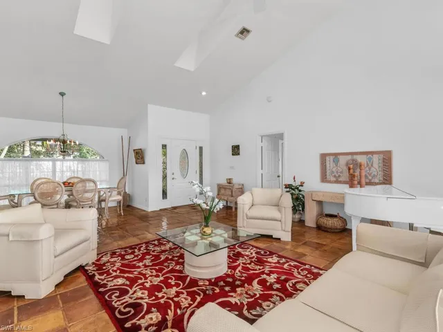 Living room with an inviting chandelier, a skylight, and high vaulted ceiling