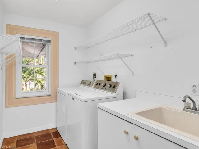 Laundry area with cabinets, separate washer and dryer, and sink