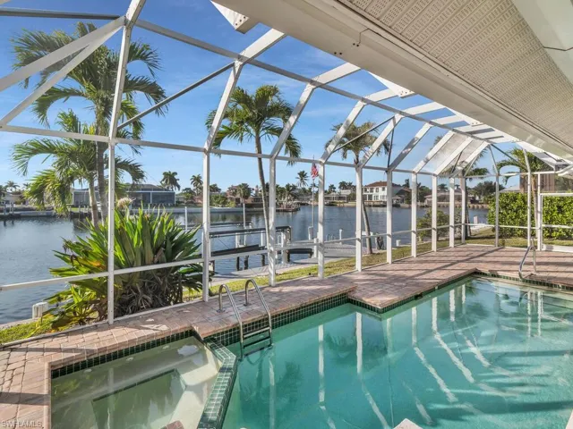 View of pool with a water view, a patio, an in ground hot tub, and glass enclosure