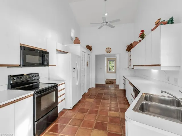 Kitchen featuring high vaulted ceiling, white cabinetry, sink, ceiling fan, and black appliances
