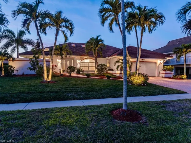 Night view featuring a garage and a lawn