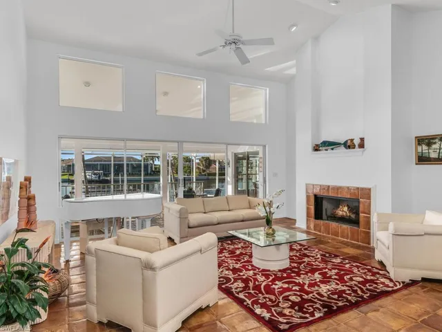 Living room featuring a tiled fireplace, high vaulted ceiling, and ceiling fan