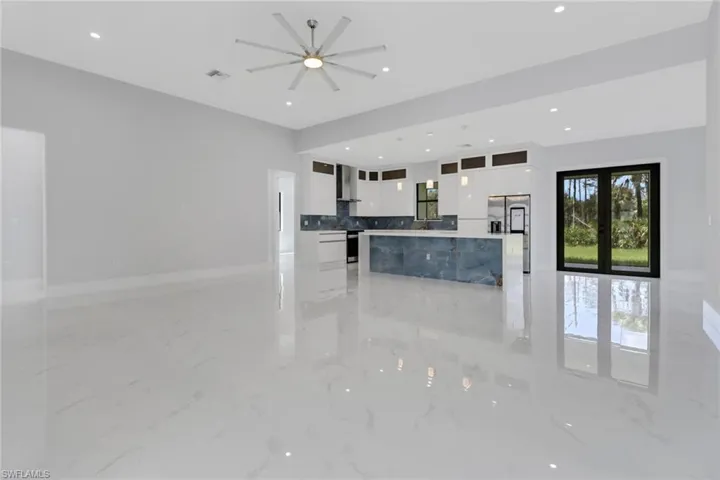 Kitchen featuring tasteful backsplash, white cabinets, wall chimney range hood, ceiling fan, and french doors