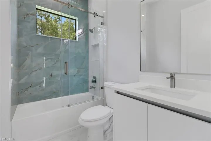 Full bathroom featuring vanity, toilet, and bath / shower combo with glass door