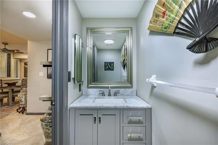 Bathroom vanity featuring a light gray cabinet with brushed nickel hardware, an integrated rectangular sink, and a stone countertop