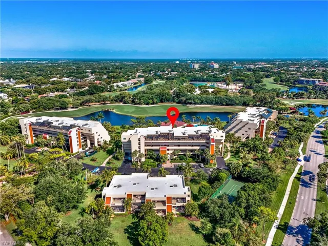 Aerial perspective showcasing multiple multistory buildings, surrounded by extensive green landscaping and mature palm trees.