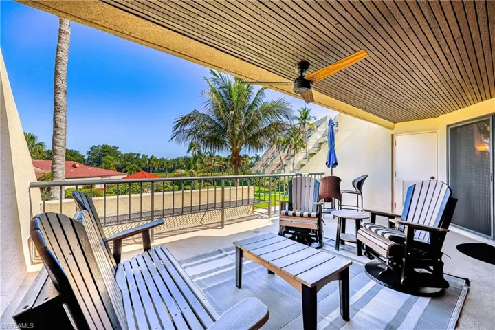 Covered balcony featuring a wood-panel ceiling, ceiling fan, privacy wall, and sliding screen door