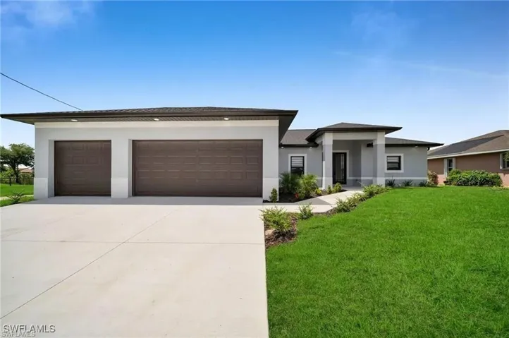 Prairie-style home featuring stucco siding, a front yard, and concrete driveway