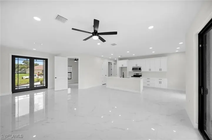 Unfurnished living room featuring recessed lighting, light marble finish flooring, ceiling fan, and french doors