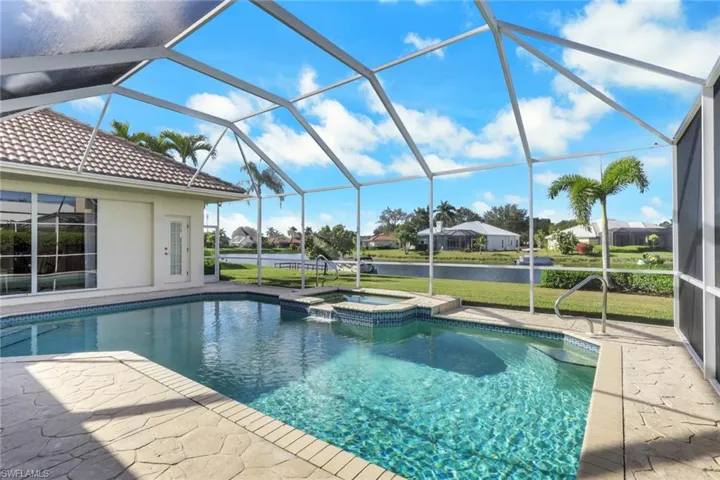 View of swimming pool featuring a sunroom, a patio area, a water view, a pool with connected hot tub, and glass enclosure