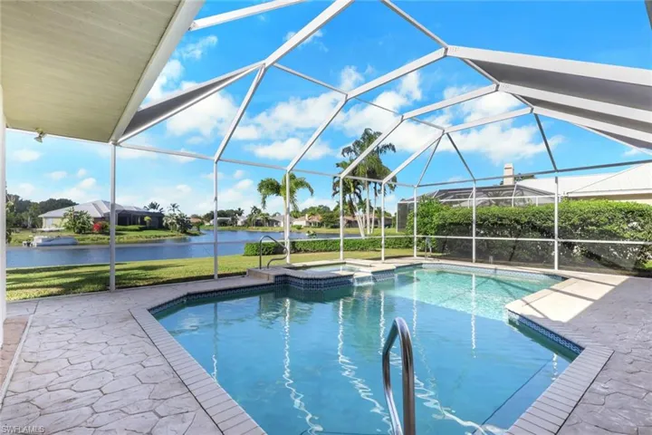 View of swimming pool with a sunroom, glass enclosure, a patio, a pool with connected hot tub, and a water view