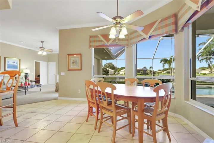 Dining space featuring a sunroom, crown molding, light tile patterned flooring, and a ceiling fan