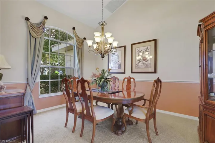 Dining room featuring light carpet, vaulted ceiling, and a chandelier