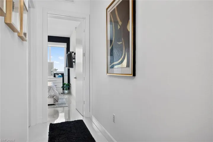 Bright hallway featuring clean white walls, white trim molding, and a black entry runner