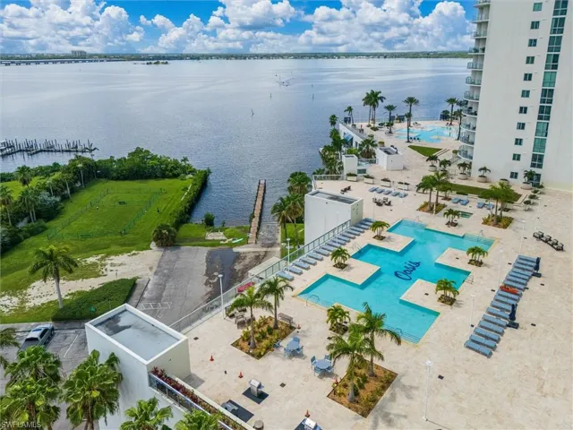 Expansive waterfront setting featuring a multi-level pool deck, a large swimming pool with integrated tanning ledges, and a separate aquatic area
