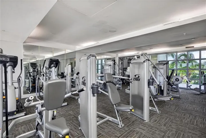 Fitness facility with multiple workout stations, full-height wall mirrors, and floor-to-ceiling windows
