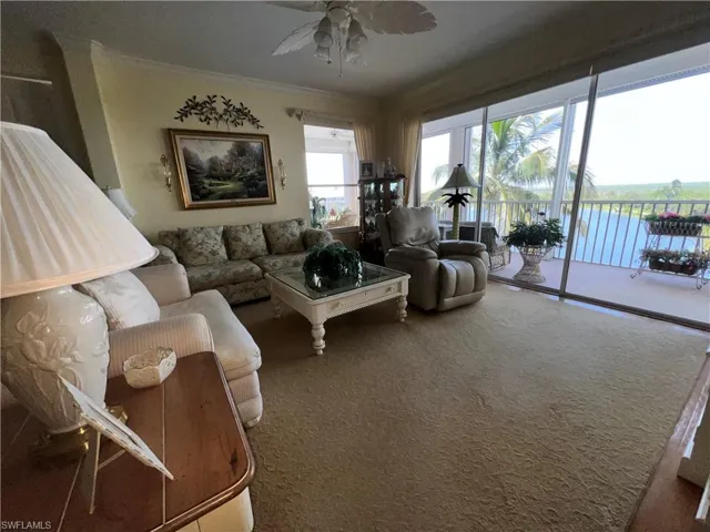 Living Room with ceiling fan, hard wood flooring, crown flooring, moldings, and a view of Waterfront Paradise