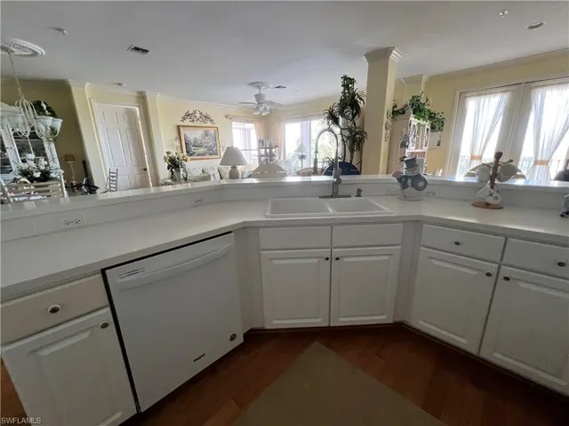 Kitchen with white appliances, white cabinets, Corian Counter-tops, Hardwood finished floors, and Cove Moldings