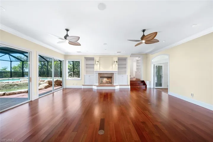 Unfurnished living room featuring ceiling fan, hardwood / wood-style flooring, built in features, and ornamental molding