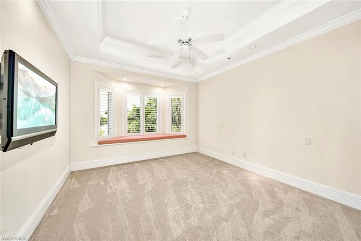 Empty room with ceiling fan, carpet flooring, ornamental molding, and a tray ceiling