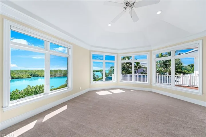 Unfurnished sunroom with a tray ceiling, a water view, and ceiling fan