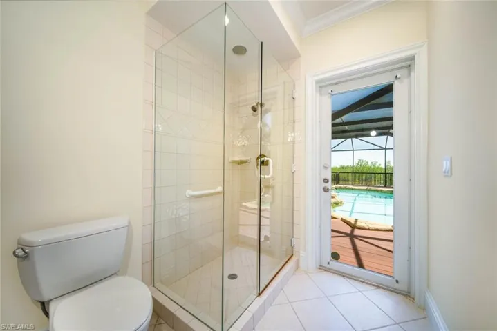 Bathroom featuring a shower with shower door, crown molding, tile patterned flooring, and toilet