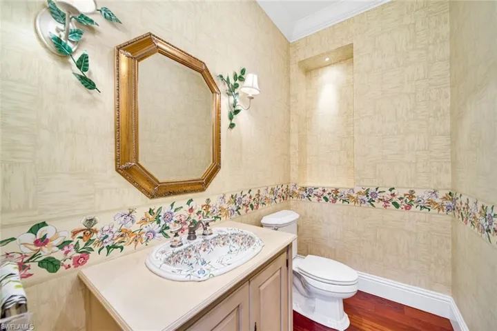 Bathroom with crown molding, toilet, vanity, tile walls, and wood-type flooring