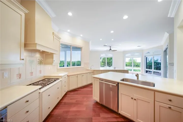 Kitchen with custom range hood, dark wood-type flooring, backsplash, appliances with stainless steel finishes, and sink